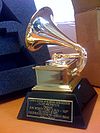 A gold gramophone trophy with a plaque set on a table