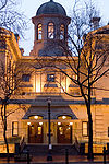 Photograph of the Pioneer Courthouse at dusk, illuminated in golden light with the cupola silouetted against the darkening sky.