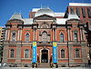 Photograph of the Renwick Gallery, an old brick building with colorful contemporary banners flanking the main entry and announcing "American Craft".