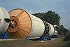 Photograph of the Saturn V Launch Vehicle on display, laying on its side outdoors and separated into segments.