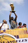 A black man is holding a trophy over his head while standing in a bus