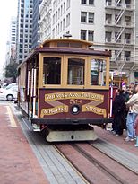 A cable car stopped next to people.