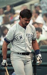 A man wearing a gray baseball uniform with navy blue stripes with "New York" written on the chest