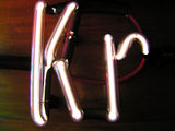 Illuminated white gas discharge tubes shaped as letters K and r