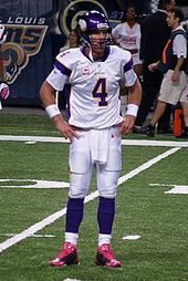 A white man wearing a purple and white American football uniform. His helmet and the sleeves of his jersey are white and there is a large numeral "4" in purple on his chest.