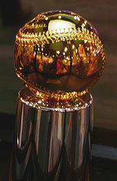 A golden baseball sitting atop a silver pedestal