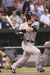 A baseball player following through on a swing. The player is wearing a gray uniform and navy baseball helmet; the uniform has a navy blue "NEW YORK" on the front, and the helmet has a white interlocking "N" and "Y" logo.