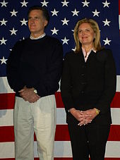 Mitt and Ann Romney standing side by side against an American flag