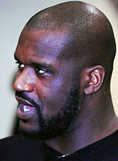 A bald, bearded black person looks toward the left, his mouth open.