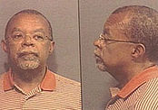 A pair of mugshots giving front and profile views of a middle-aged African American man with very short-trimmed dark hair very short-trimmed grey goatee and mustache, a neutrally nondescript or matter-of-fact expression on his face, wearing very lightweight wire-rimmed eyeglasses and an orange-and-white variegated-pinstripe polo shirt.
