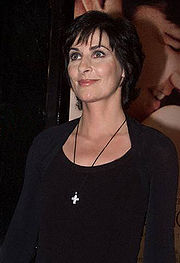Lady with dark hair wearing a black top and a crucifix necklace.