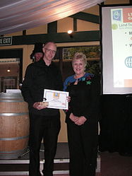 Minister Annette King standing next to Rick Houghton, who is holding a certificate