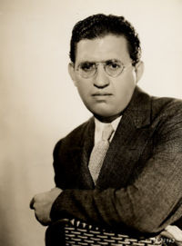head shot of a well-dressed man wearing glasses