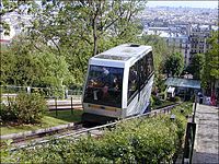 Photograph looking down the outlier (French: butte) of Montmartre showing the back and roof of a cabin. A panorama of Paris below fills the background.