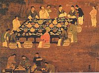 Twelve people gather around an outdoor table decorated with a black tablecloth, several potted plants, and dozens and dozens of small dishes. Most of the people are talking with one another. Off to the side a servant stands watching, and in the bottom of the painting four people are crowded around a smaller table set up as a staging area for the preparation of tea.