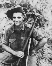 An informal portrait of a man in military uniform holding a rifle.