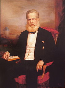 Painted portrait of bearded man in formal dress seated in an armchair with his left hand turning a page of an open book
