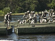 A group of soldiers in green fatigues assembling a bridge