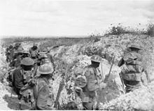 Heavy laden soldiers move through a communication trench during the daytime