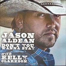 An image of a man wearing a white cowboy hat, looking aside. He is wearing a blue shirt and his right ear is pierced. Next to him the words "Jason Aldean Don't You Wanna Stay" and "with Kelly Clarkson" are written in white color.