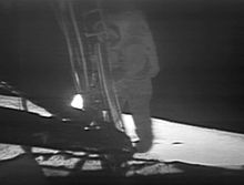 A low-quality photo of a television monitor showing Armstrong on the lunar module's ladder