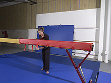 Gymnastics coach fastening a foam wrap to the balance beam.