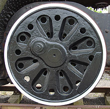 An almost solid disc (not spoked) locomotive wheel with a series of cast-in radial indentations and prominent round holes intended to reduce its weight.