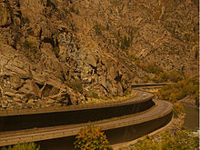 A two tiered highway snaking around bends in a canyon, with some fall foliage visible