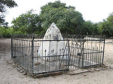 A white pyramid surrounded by a metal fence with trees in the background
