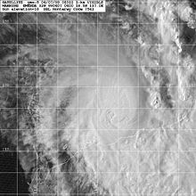 Satellite image of a weakening tropical cyclone. The cloud cover of the storm is becoming elongated to the north and east and constrained elsewhere. No eye is present within the storm. Part of Northwestern Australia can be seen at the bottom-right of the image.