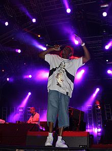 A man rapping on stage, with purple spotlights behind him