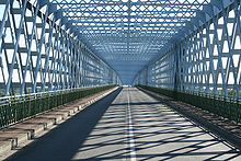 A two-lane road caged in intertwined steal bars, in a style reminiscent of the Eiffel tower.