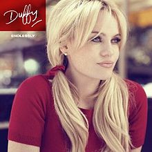 Image of a blonde woman wearing a red T-shirt with her hair in pigtails and with her arms drawn in to her sides. She is staring off-centre to her left and the background appears to have been blurred. In the left corner, the word "Duffy" is written in a red box in signature style. Below is the word "ENDLESSLY" in smaller writing.