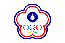 A white symbol in shape of a five petal flower ringed by a blue and a red line. In its center stands a circular symbol depicting a white sun on a blue background. The five Olympic circles (blue, yellow, black, green and red) stand below it.