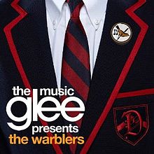 Close-up of a male private school uniform, showing a white dress shirt with a blue and red blazer and tie. A crest with a styled 'D' as well as a lapel pin featuring a yellow bird are located on the wearer's left. The words "Glee", with "The Music" above and "Presents The Warblers" below, appear to the bottom right in minuscule font.