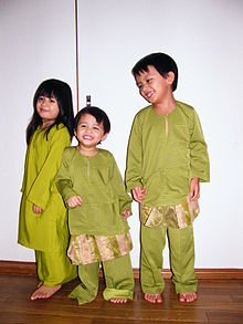 A Malay girl and two Malay boys dressed in green traditional clothing