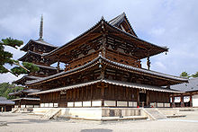 A large wooden building with a hip-and-gable main roof and a secondary roof giving the impression of a two-story building. Between these roofs there is an open railed veranda surrounding the building. Below the secondary roof there is an attached pent roof. Behind the building there is a five-storied wooden pagoda with surrounding pent roof below the first roof.