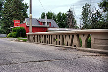 A small concrete bridge crosses a stream.  The sides of the bridge were designed to spell out "Lincoln Highway".