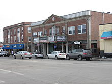 Three buildings in a small New England square; in the center is a two-story theater with a marquee