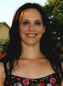 Picture of a 28-year-old woman with a black, open hair up to breast level and a wide smile