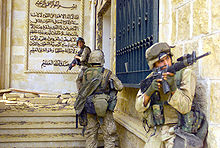 color photo of three Marines entering a partially destroyed palace