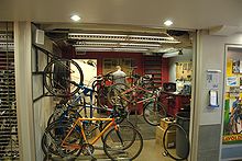 Two men standing beyond an island of lockers with bikes visible on bike racks to the left