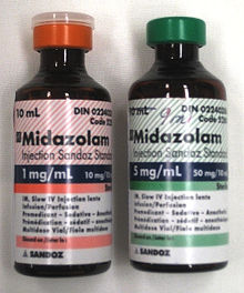 Two 10 mL bottles labeled Midazolam. The bottle on the left has a label in red and says 1 mg/mL; the one on the right is in green and says 5 mg/mL. Both bottles have much fine print.