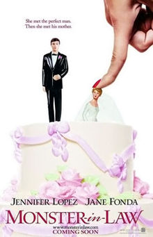 A wedding cake with figurines of the bride and groom. A finger pushes the bride into the cake.
