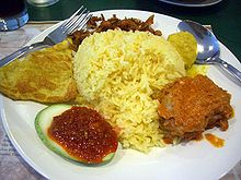 A dish of rice surrounded by various condiments