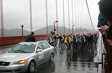 A bunch of bicyclist following a car.