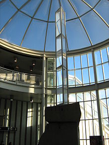 A tall prism sculpture in a glass atrium.