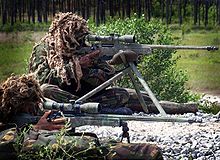 Two marines in ghillie suits air rifles one sitting, one prone