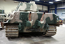 The overhanging rear face of a large tank, two laterally spaced exhaust pipes protrude from mountings, pointing upwards, curving away from the vehicle at their ends.