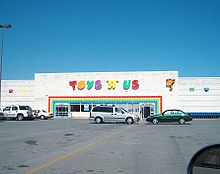 Large, white Toys "R" Us store under blue sky, with parking lot in front